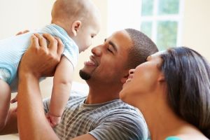 Young Family Playing With Happy Baby Son At Home