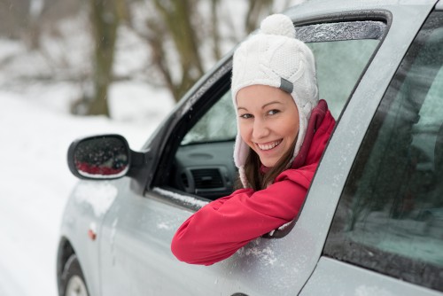 Woman driving in winter on snow covered slippery road in forest