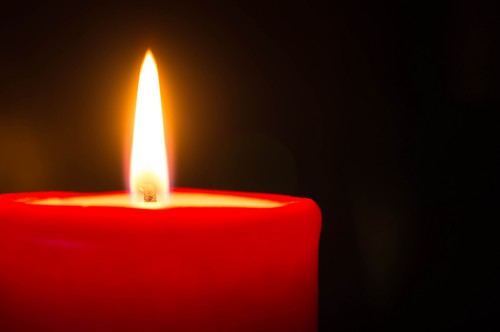 Red candle against a dark background close up