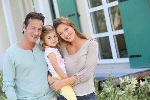 Portrait of happy family standing in front of house